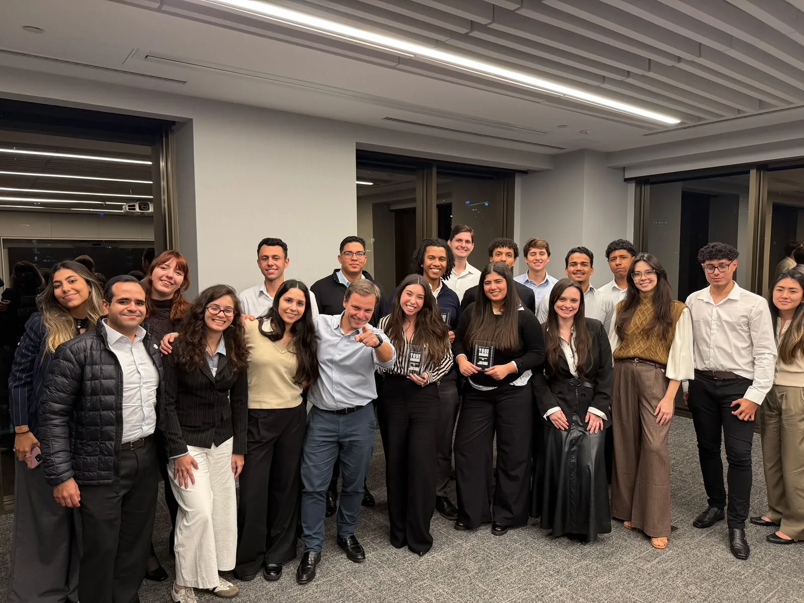 Alumni e participantes do You in Banking no evento de encerramento com os troféus do programa